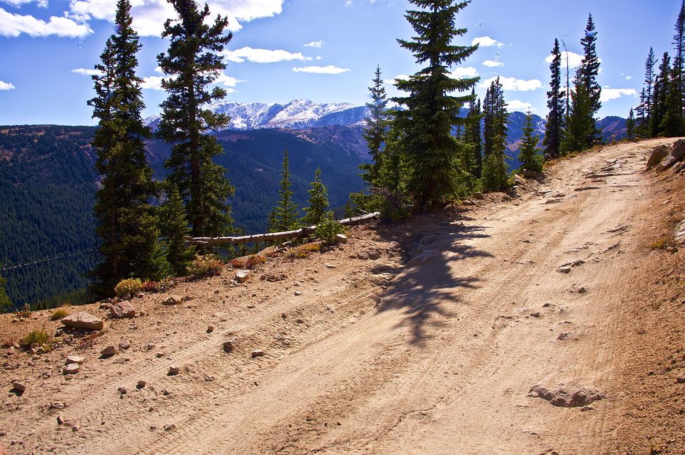 A rough dirt road on the east side of Hagerman Pass with spruce and distant peaks