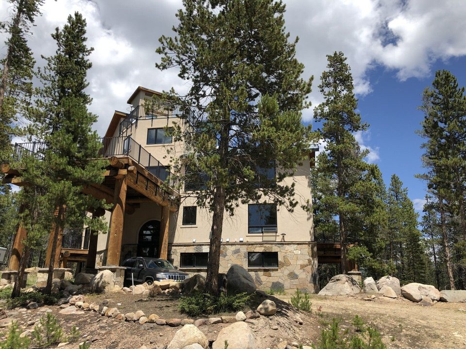 A four-story lodge with log posts, stone base and iron-railed decks among lodgepole pines