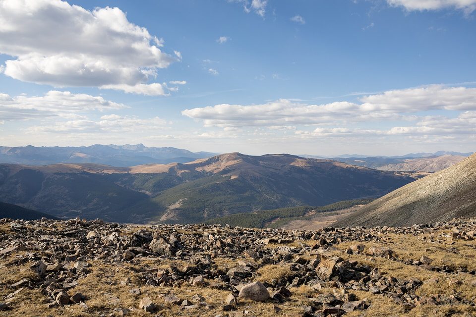 Rocky tundra in the foreground and layered mountain ridges under big clouds, seen from Mosquito Pass